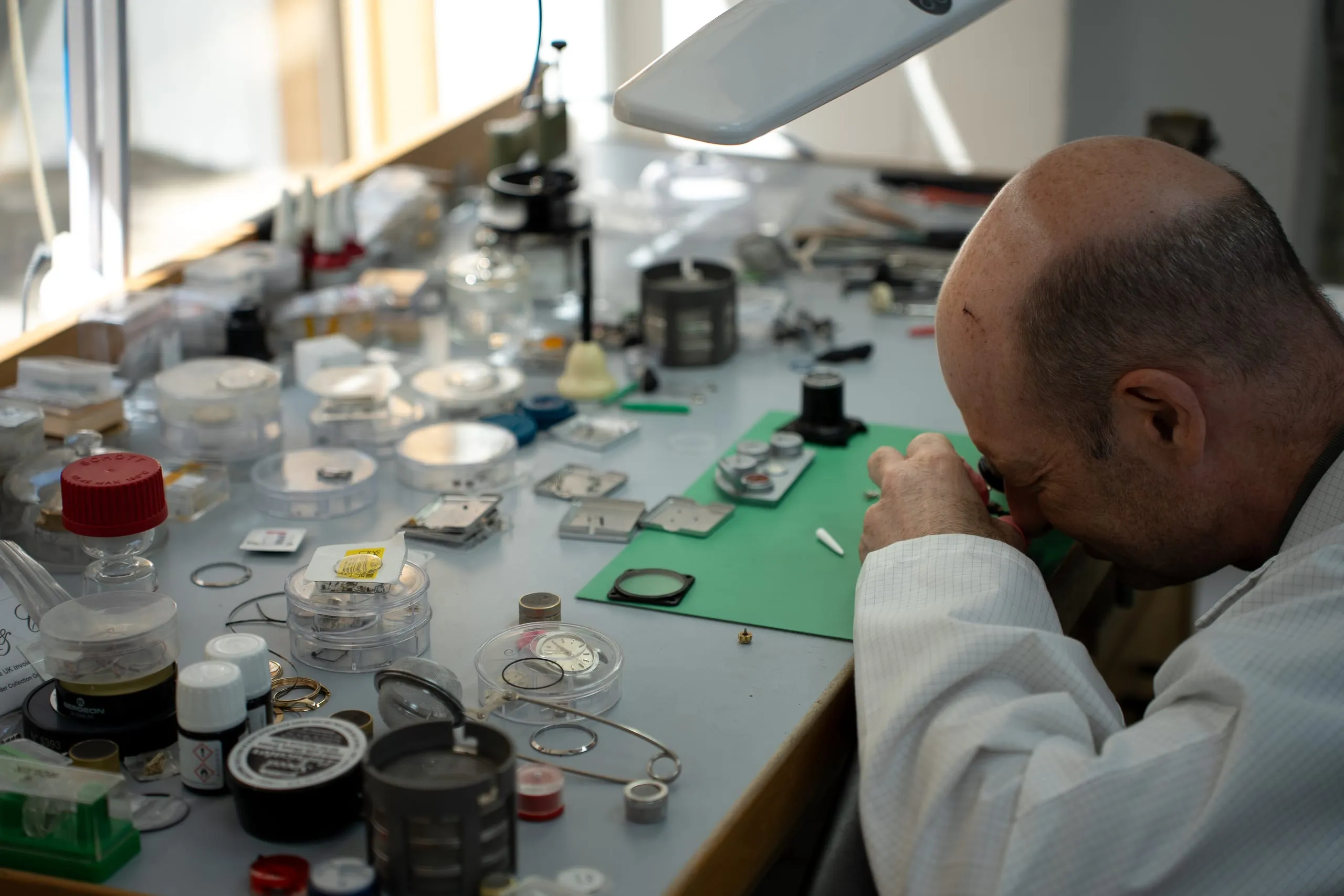 Senior SwissMade watchmaker working under a loupe at the bench
