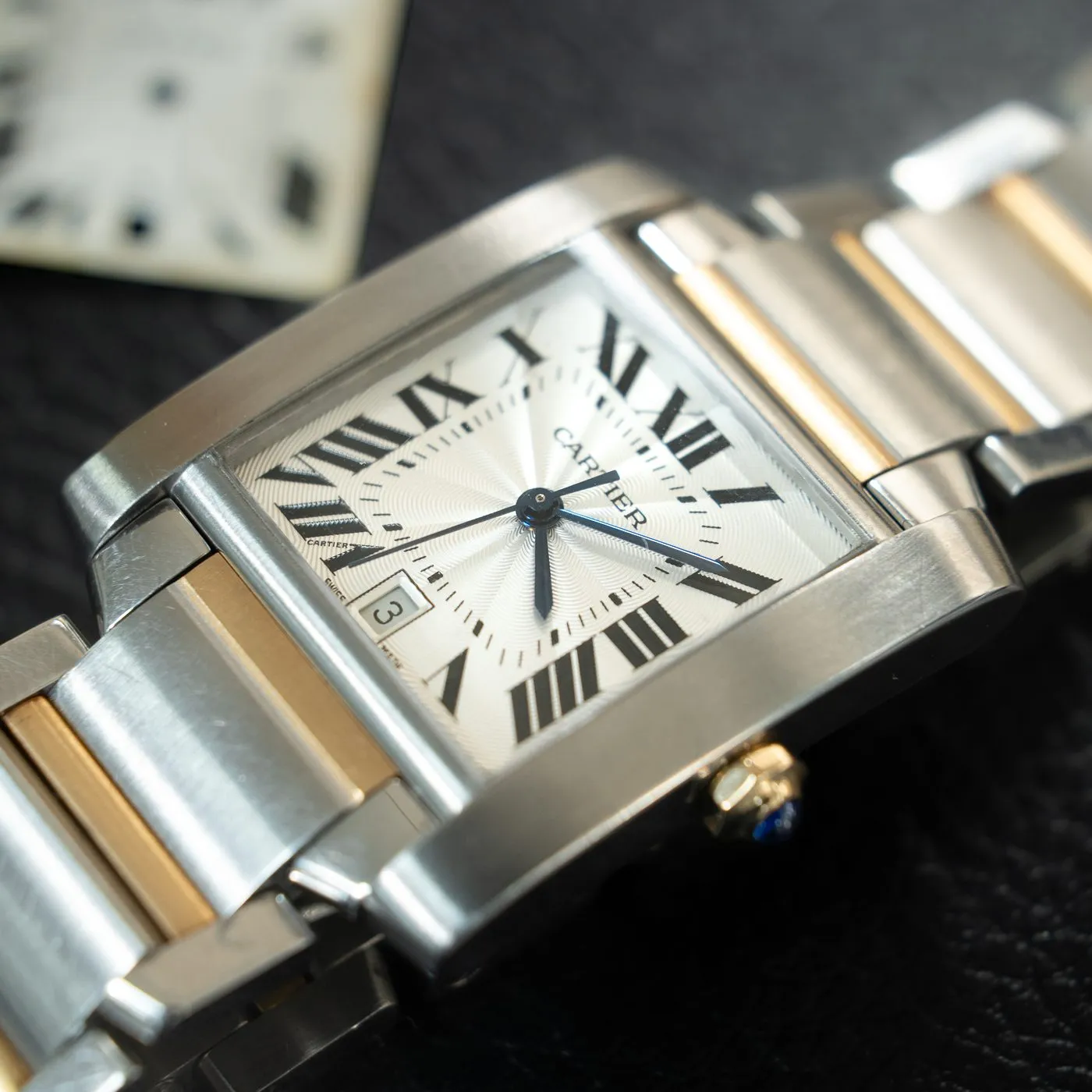 Two-tone Cartier Tank Française beside a removed dial on the SwissMade bench