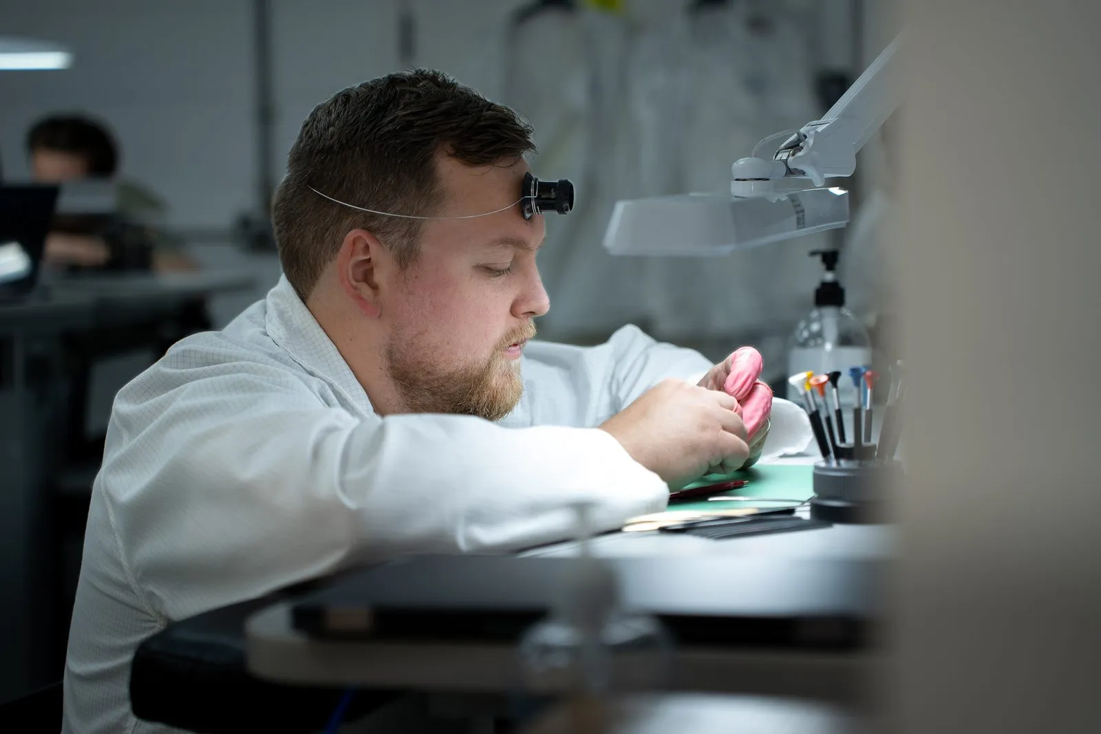 SwissMade watchmaker examining a movement through a loupe at his bench