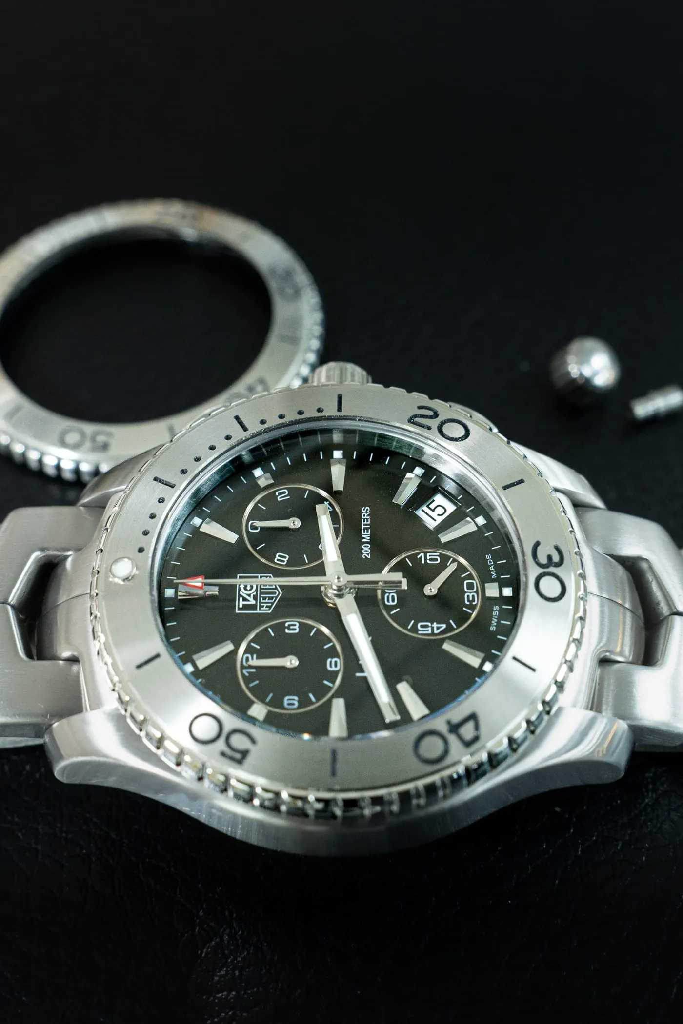 TAG Heuer Aquaracer chronograph beside a removed bezel on the bench at SwissMade