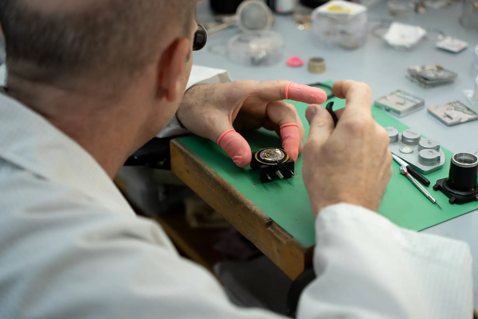 SwissMade watchmaker examining a movement through a loupe
