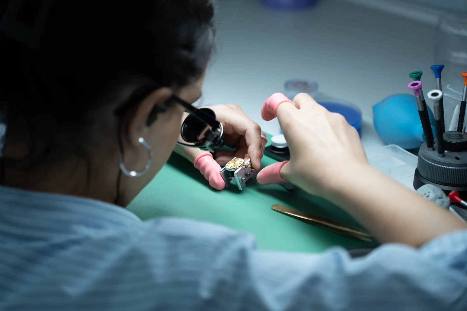 SwissMade watchmaker working through a loupe on a vintage movement at the bench
